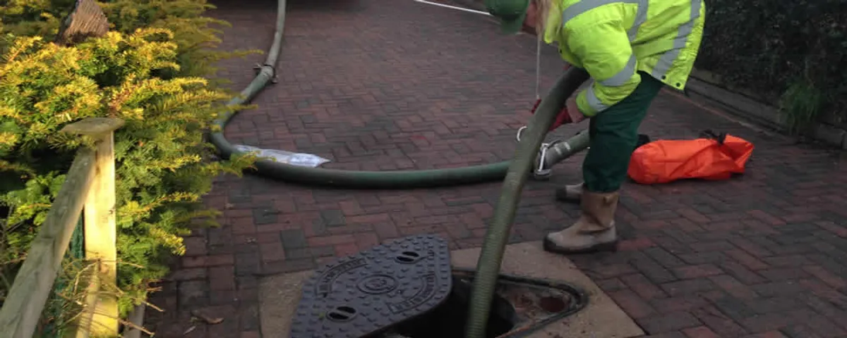 Septic tank cleaning technician servicing a septic tank with a vacuum hose in Marietta, GA