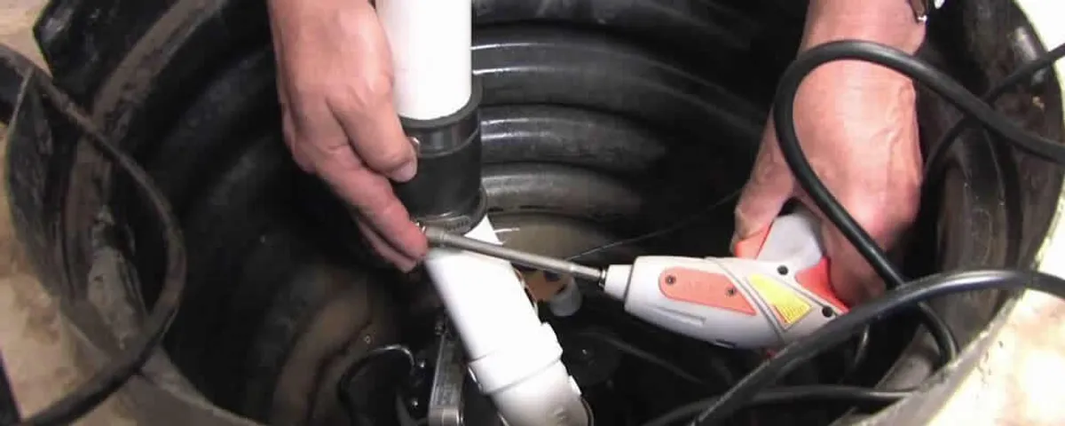 Sump pump installation technician connecting PVC discharge piping in Marietta, GA