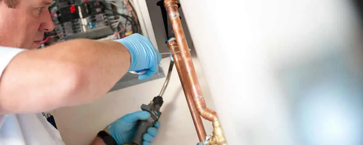 Water heater repair technician testing copper pipe connections and controls in Marietta, GA